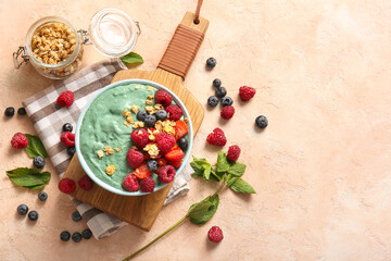 Napkin, bowl with tasty spirulina smoothie and berries on pink grunge background