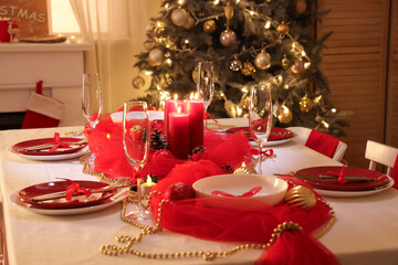 Christmas table setting with burning candles in dark room
