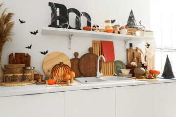 Interior of light kitchen decorated for Halloween with white counters and shelf