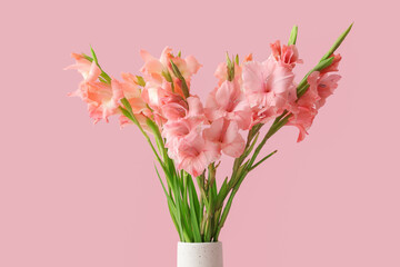 Vase with bouquet of beautiful gladiolus flowers on pink background