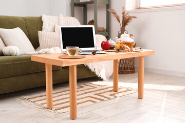 Cup of green tea near laptop on table in room