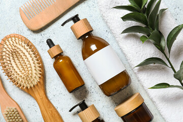 Composition with bottles of shampoo, hair brushes and green twig on white grunge background