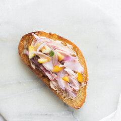 Overhead view of open sandwich with chicken yellow tomatoes and peppers, top view of sandwich appetizer on a marble background