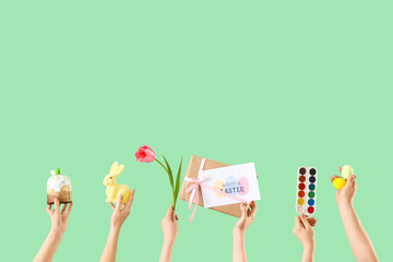 Female hands with Easter decor, paints and tulip on green background