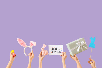 Female hands with Easter decor and gift on lilac background