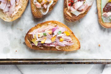 Overhead view of open sandwiches with chicken yellow tomatoes and peppers, top view of sandwich appetizer on a marble background