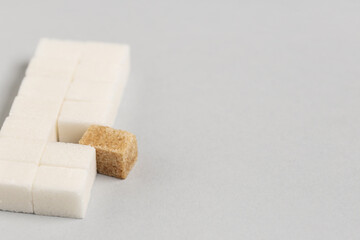 Brown and white sugar cubes on grey background, closeup