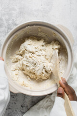 Overhead view of bread dough being mixed in a donabe, top view of homemade bread dough being mixed on granite countertop, process of making artisan bread
