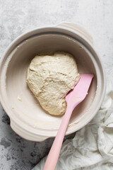 Overhead view of focaccia dough on a white marble countertop, top view of homemade focaccia bread dough in a claypot, process of making focaccia