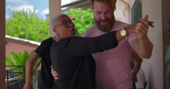 Man and woman from diverse backgrounds dancing joyfully with family and friends during an outdoor celebration, embracing connection and multicultural harmony