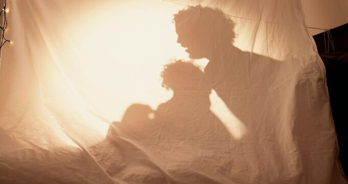 Tent, home and shadow with family, playing and games with weekend break, love and relax. Parents, apartment and child in living room, toys and bonding together with dad, storytelling and silhouette