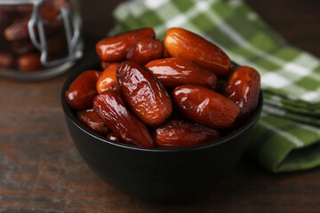 Tasty dried dates in bowl on wooden table, closeup