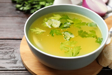Tasty chicken bouillon in bowl on wooden table, closeup