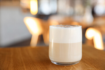 Glass of aromatic coffee on wooden table in cafe, closeup. Space for text
