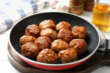 Tasty meatballs in frying pan on white table, closeup