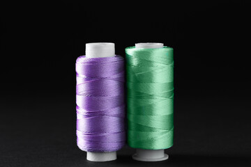 Spools of colorful sewing threads on black background