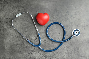 Cardiology. Stethoscope and red decorative heart on gray textured background, flat lay