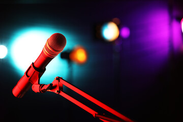 Microphone on stand against color background with blurred lights, space for text. Bokeh effect