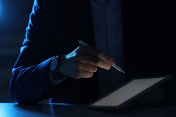 Electronic signature. Man with stylus and tablet at table in dark office, closeup