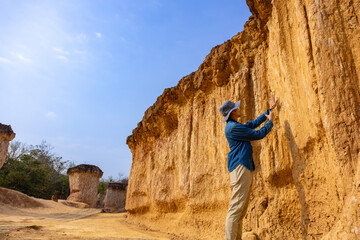 Asian geologist is exploring and surveying the sample rock on the natural sandstone canyon quarry...