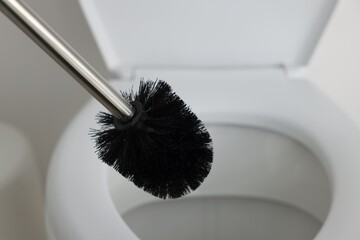 Black toilet brush and bowl indoors, selective focus