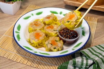 A plate of dim sum on a tin plate and hold with chopsticks. A traditional Chinese food.