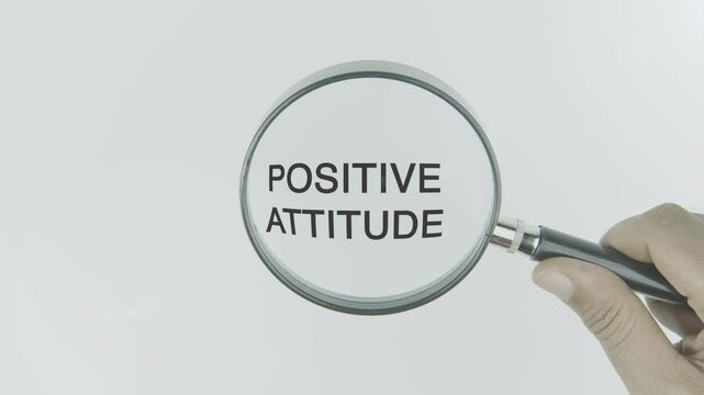 Positive attitude text or word highlighted by a magnifying glass in a hand on a white background, symbolizing focus on optimism, mindset, and the power of maintaining a constructive outlook