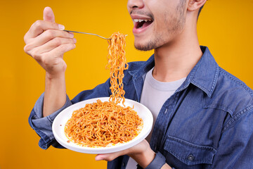 Close Up Of Young Man Picking Up Fried Noodles Ready To Eat Isolated On Yellow Background