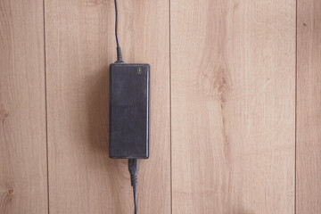 Power adapter resting on wooden surface with cable attached