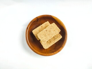 Satru cake, Satu cake, or Koya cake on a wooden plate with white background. This traditional Indonesian Javanese pastry is made from processed sago and mung beans.