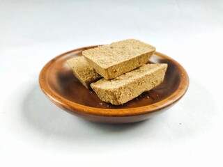 Satru cake, Satu cake, or Koya cake on a wooden plate with white background. This traditional Indonesian Javanese pastry is made from processed sago and mung beans.