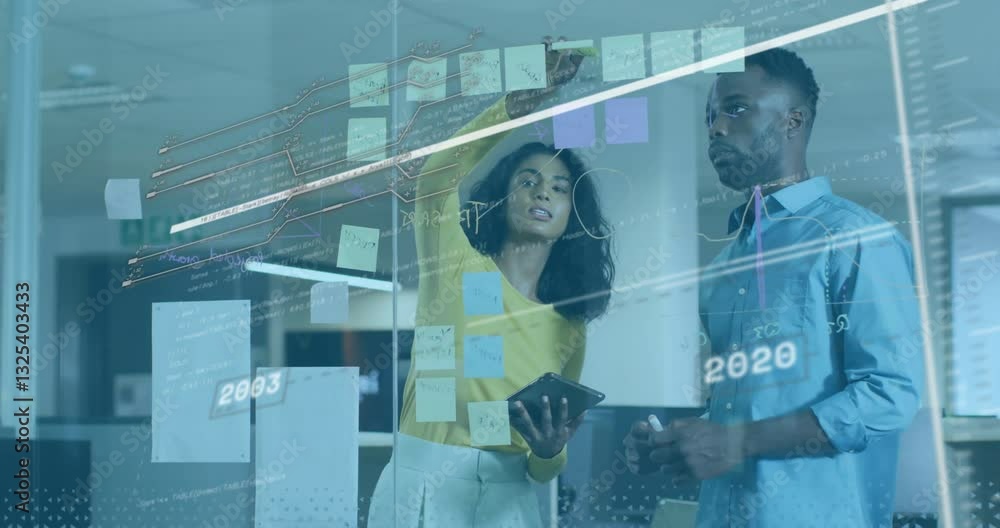 Poster analyzing data with digital graphs and sticky notes, business professionals in office