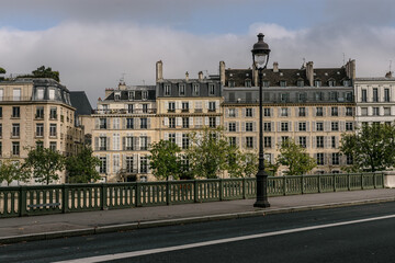 Paisaje urbano de París con avenida con faroles en primer plano y al fondo arquitectura típica.