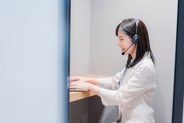 シェアオフィスの個室ブースでリモート会議をする女性