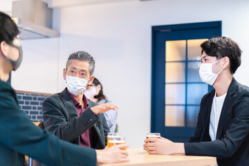 マスクをしてレストランで会話をする人々