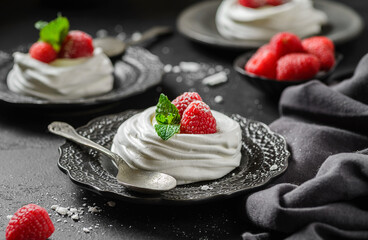 pavlova meringue dessert with raspberries and cream on a black background