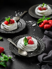 pavlova meringue dessert with raspberries and cream on a black background