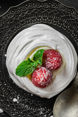 pavlova meringue dessert with raspberries and cream on a black background