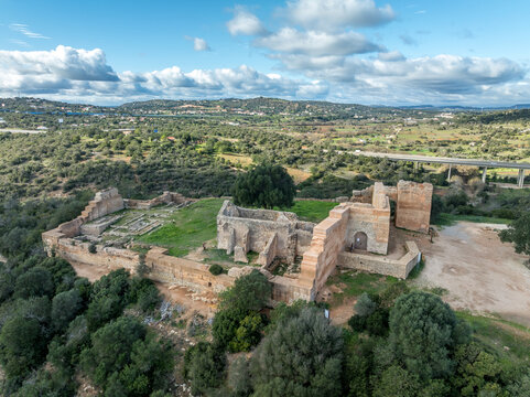 Stone ramparts & crenellated walls define Paderne Castle's medieval architecture, a historic Portuguese fortress against a blue sky