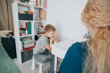 young boy with adhd struggles with focus during a learning session at home, guidance by a child psychotherapist, concept of special education and supportive learning environments