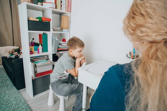 young boy with adhd struggles with focus during a learning session at home, guidance by a child psychotherapist, concept of special education and supportive learning environments