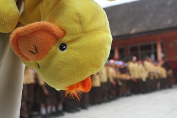 yellow duck doll upside down with people in a row in the background