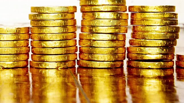 Macro of gold coins piling up on a wooden floor