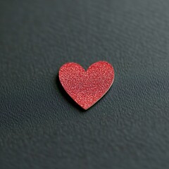 Obraz premium A shimmering red heart sits alone on a textured black surface