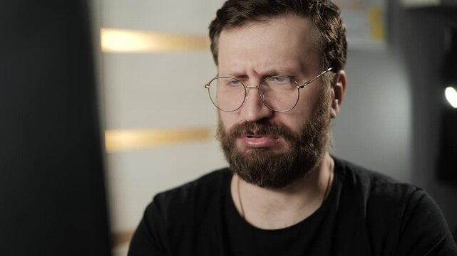Disgust, dissatisfied, irritated concept. Negative bearded man with glasses looking at computer screen and seeing disgusting content
