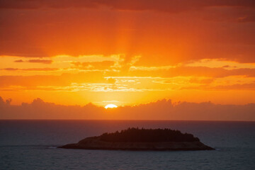 A colorful sunset over the ocean with a small island in the distance