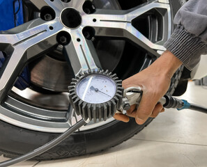Tire pump inflating car wheel. Tyre inflator in man hands with manometer. Hand car mechanic holding...