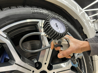 Tire pump inflating car wheel. Tyre inflator in man hands with manometer. Hand car mechanic holding...