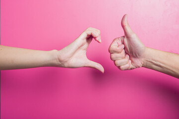 Asian hands facing each other on a bright pink background&mdash;one forming a heart-like C shape, the other giving a thumbs up. Symbolizes approval, care, and emotional connection in creative design context