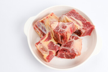 Raw beef ribs or daging iga sapi on white plate, food preparation.
